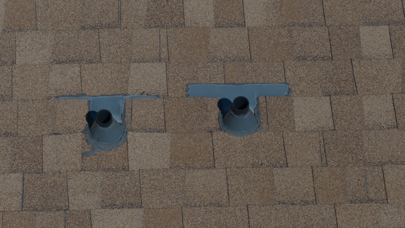 Close-up of sealed pipe boots on tan asphalt shingles