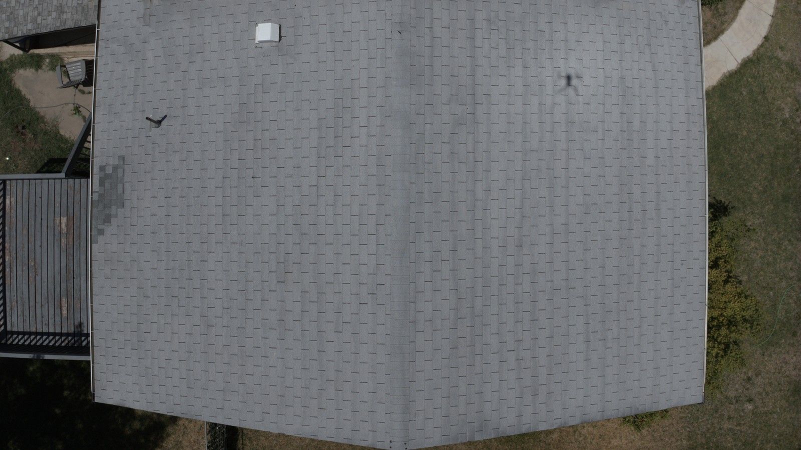 Overhead view of weathered gray asphalt shingles with a roof vent and pipe boot, the kind of detail a roof inspection documents