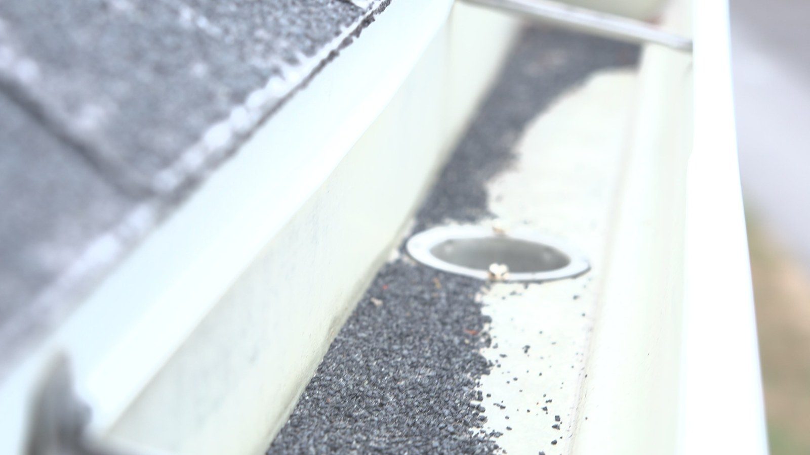 Gutter with shingle granules collected around the downspout outlet