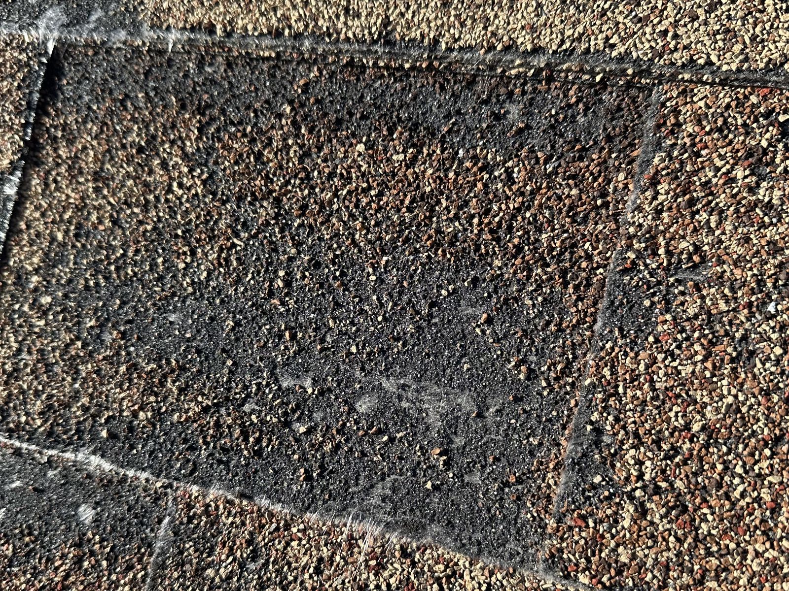 Close-up of a worn asphalt shingle with heavy granule loss