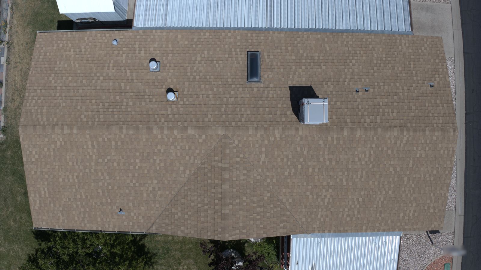 Overhead view of an asphalt shingle roof with roof vents and a skylight