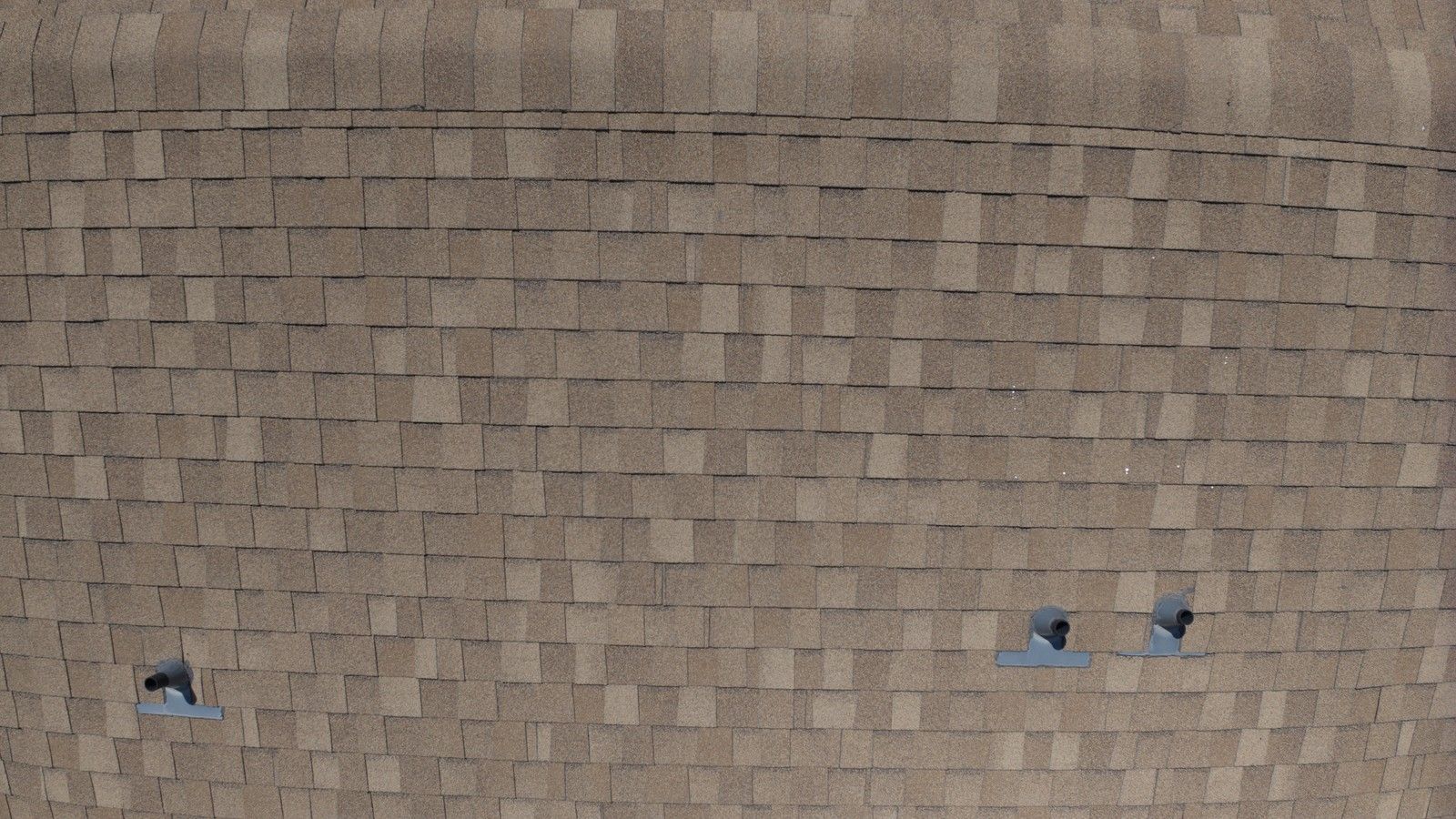 Close aerial of asphalt shingles and pipe-boot flashing, the details an inspection checks before recommending rejuvenation