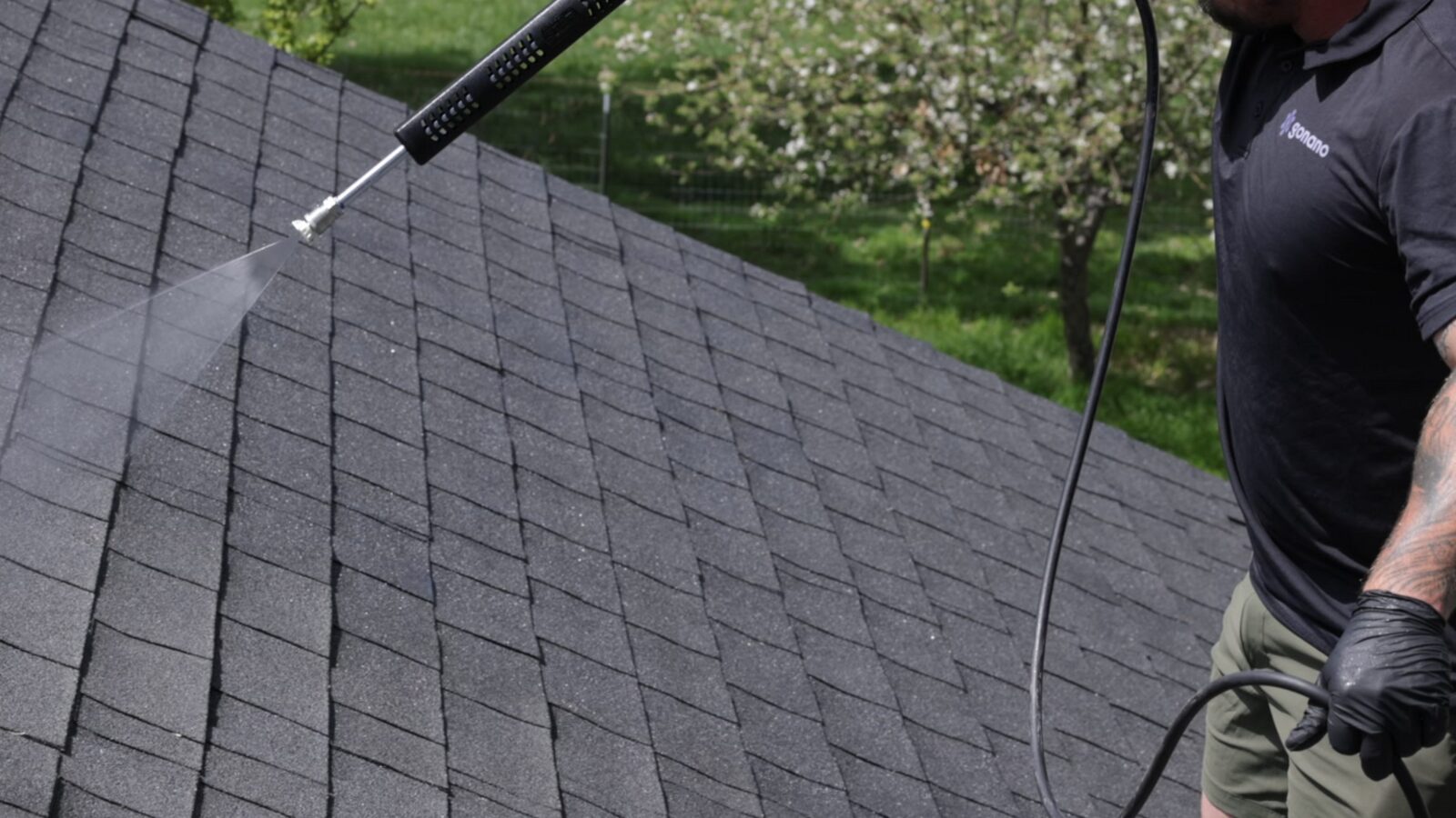 Helping restore asphalt shingle flexibility with hose-fed GoNano, applied by a technician on the roof. The NuRoof Guys.