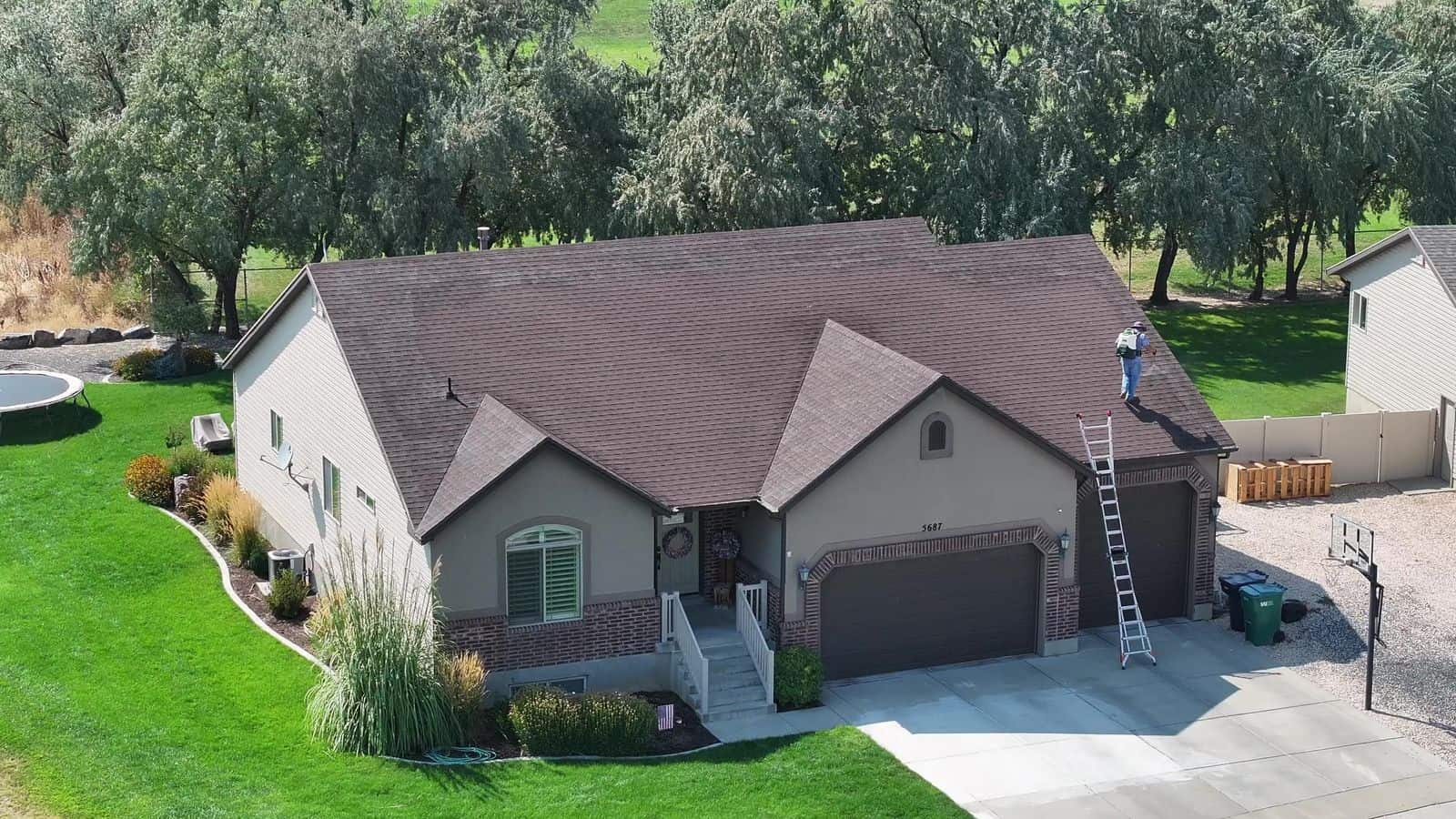 Aerial view of a home with a brown shingle roof in summer. The NuRoof Guys.