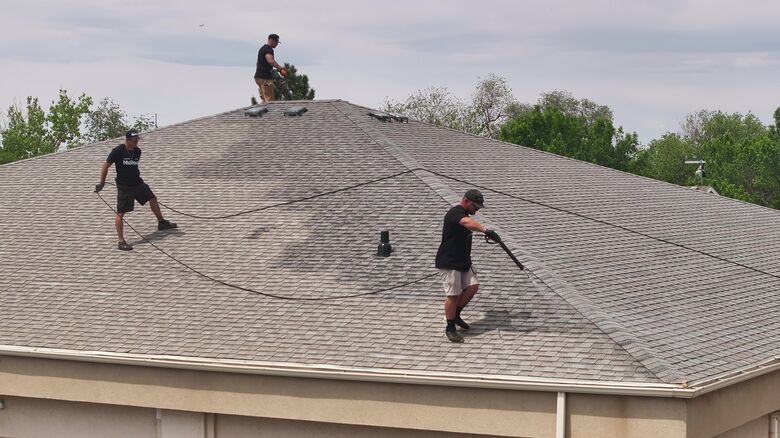 Crew applying hose-fed GoNano across asphalt shingles in Utah.